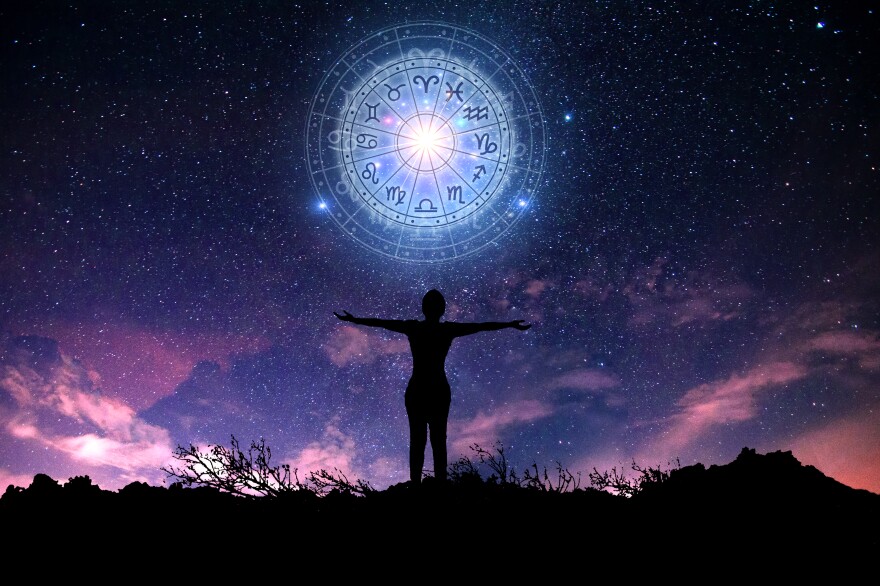 Psychological transformation at 29, 58, and beyond: a person standing with open arms beneath a glowing zodiac wheel in a starry night sky