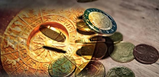 Wealth and poverty in astrology: falling coins overlaid on a golden engraved zodiac wheel