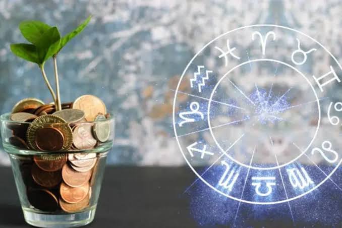 Wealth astrology: a glass jar of coins with a green sprout growing from it beside an illuminated zodiac wheel